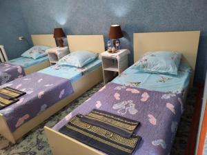 a room with three beds and two night stands at LION Guest House in Bukhara