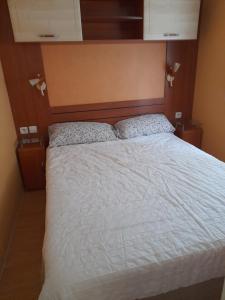 a bedroom with a large bed with white sheets at Mobil home camping les écureuils in Mimizan