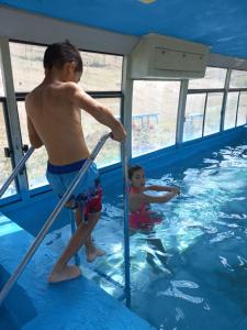 deux jeunes garçons jouant dans une piscine dans l'établissement Guest House AREVIK, à Artsvakar