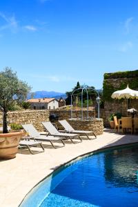 une piscine avec des chaises longues à côté d'un mur en pierre dans l'établissement CASA SANTA MARIA, à Santa-Reparata-di-Balagna