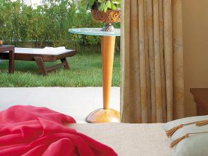 Grecotel Larissa Imperial في لاريسا: طاولة مع مزهرية فوق السرير