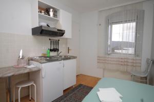 eine kleine weiße Küche mit einem Waschbecken und einem Fenster in der Unterkunft Apartments by the sea Komiza, Vis - 9703 in Komiža