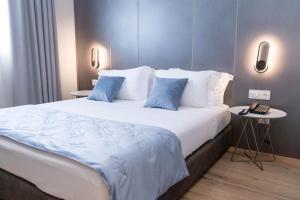 ein Schlafzimmer mit einem großen weißen Bett mit blauen Kissen in der Unterkunft HOTEL PATIO in Vlorë