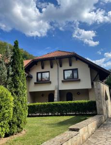 une maison avec deux fenêtres et une haie dans l'établissement Вила 11 - семейна почивка в сърцето на Балкана, à Ribarica