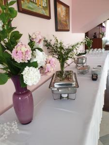 a long white counter with vases of flowers on it at Hotel Rytwiany in Rytwiany