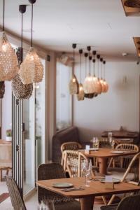 a restaurant with wooden tables and chairs and chandeliers at Hotel Boutique & Spa Las Mimosas Ibiza in San Antonio Bay