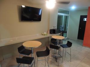 Habitación con 2 mesas y taburetes y TV en la pared en Hotel Metropolitano Tampico en Tampico