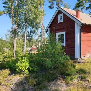 a red house in the middle of a field at Cabin near lake and beautiful nature reserve. in Bodafors