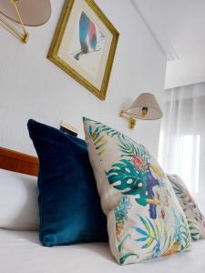 łóżko z 2 niebieskimi poduszkami i zdjęciem na ścianie w obiekcie Pension Uxarte w mieście Arrasate - Mondragon