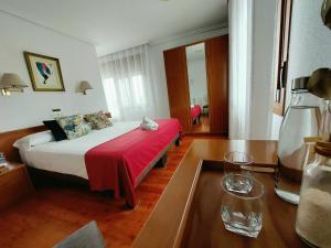 um quarto de hotel com uma cama com um cobertor vermelho em Pension Uxarte em Arrasate