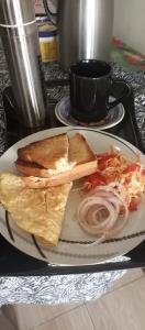 a plate of food with a sandwich and onions at Puma Garden and Suites - Nyarutarama in Kigali