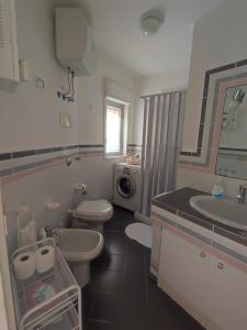 une salle de bain avec deux toilettes et un lavabo et une machine à laver dans l'établissement Villa Bouganvilla, à Cefalù