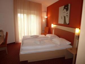 a bedroom with a white bed with an orange wall at Gasthof zum Bad in Langenau