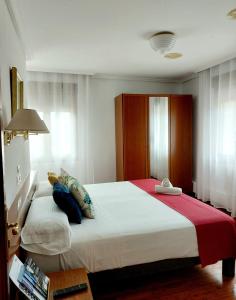a bedroom with a large white bed with a red blanket at Pension Uxarte in Arrasate - Mondragon