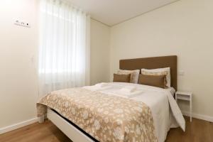 um quarto com uma cama grande e uma janela grande em Senhora da Agonia - Apartment in Ribeira em Viana do Castelo