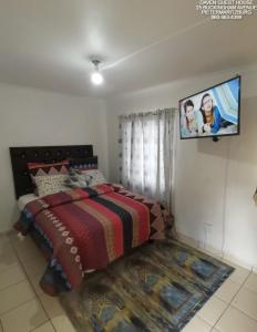 a bedroom with a bed and a tv on the wall at Daven Guest House in Pietermaritzburg