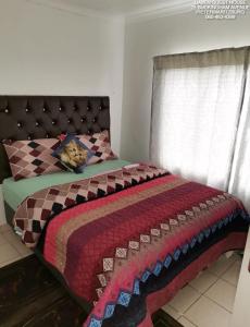 a bedroom with a bed with a blanket and a window at Daven Guest House in Pietermaritzburg