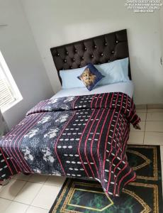 a bed with a blanket and pillows on it at Daven Guest House in Pietermaritzburg