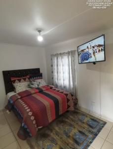 a bedroom with a bed with a tv on the wall at Daven Guest House in Pietermaritzburg