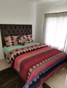 a bedroom with a bed with a quilt on it at Daven Guest House in Pietermaritzburg