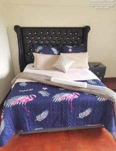 a bed with a blue quilt with pink flamingos on it at Daven Guest House in Pietermaritzburg
