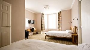 ノリッジにあるMarlborough Hotelのベッド2台とデスクが備わるホテルルームです。