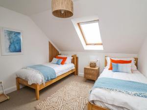 a attic bedroom with two beds and a window at Ty Ni in New Quay