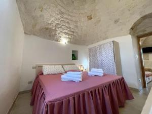 ein Schlafzimmer mit einem rosa Bett mit Handtüchern darauf in der Unterkunft VALLE D'ITRIA Trullo Sovrano sul Monte in Cisternino