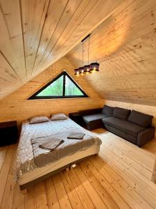 um quarto com uma cama, uma janela e um sofá em Całoroczne domy z bala - CASA DEL CZYŻYK em Serwy