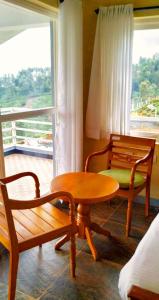 Zimmer mit 2 Stühlen, einem Tisch und einer Bank in der Unterkunft Mysterious mountain in Udagamandalam