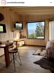 Zimmer mit einem Bett, einem Tisch und einem Fenster in der Unterkunft Punta Ballena Lodge in Pichilemu