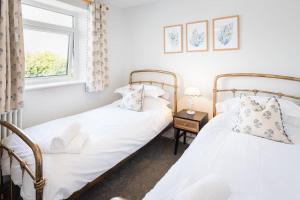 two twin beds in a room with a window at *Brand New* Olive Grove Cottage in Torquay