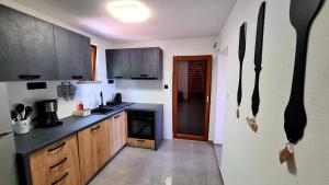 Una cocina con gabinetes de madera y una encimera negra. en Holiday house with a parking space Milovac, Paklenica - 15168, en Starigrad-Paklenica 12 fotos más