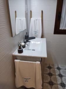 ein Badezimmer mit einem Waschbecken, einem Spiegel und Handtüchern in der Unterkunft Apartamento Turístico El Empedrado de M&G in Colmenar de Oreja