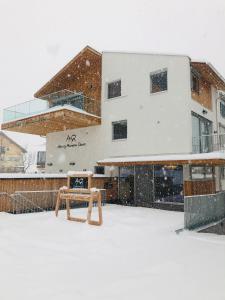 un edificio cubierto de nieve con un banco delante en Arlberg Mountain Resort, en Pettneu am Arlberg