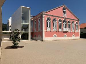 um edifício vermelho com uma árvore em frente em HI Vila do Conde - Pousada de Juventude em Vila do Conde