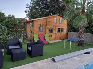 a tiny house with chairs and a table and a pool at Casa di legnu ,charmant chalet avec piscine in Patrimonio