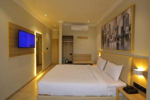 a bedroom with a large white bed and a tv at Hotel City Express By Downtown in Udaipur