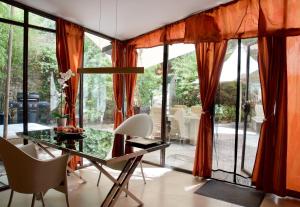 LASUITE Domaine Bertuli, heated Pool, Aircon في اوبيديه: غرفة طعام مع ستائر برتقالية وطاولة زجاجية وكراسي