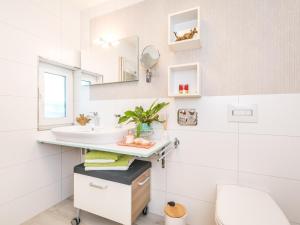 un bagno bianco con lavandino e specchio di Ferienwohnungen SIRI a Burgstaedt Altre 39 foto