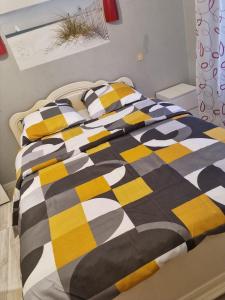 Una cama con una manta negra y amarilla. en Belle chambre avec balcon, en Arques
