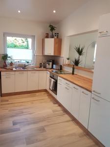 a kitchen with white cabinets and a wooden floor at Oase am Nationalpark in Kargow