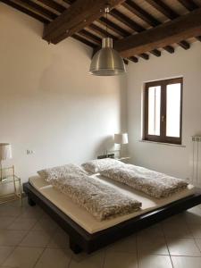 Cama grande en habitación blanca con ventana en Casa Ornella, en Nocera Umbra