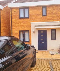a car parked in front of a brick house at Modern home with Netflix, NowTV & 2private parking in East Tilbury