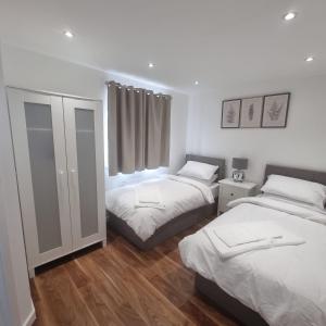 1 dormitorio con 2 camas y ventana en Modern home with Netflix, NowTV & 2private parking en East Tilbury