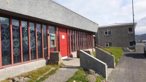 a building with a red door next to a street at The Bank Sleeping in Neskaupstaður