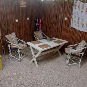 a white table and two chairs and a wooden wall at Casa Carlotta & Villa in Nungwi