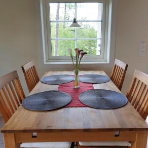 a wooden table with four plates and a vase with flowers on it at Cabin near lake and beautiful nature reserve. in Bodafors