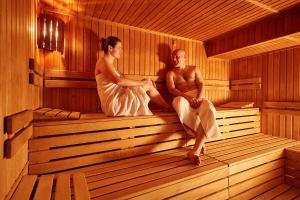 Ein Mann und eine Frau sitzen in einer Sauna in der Unterkunft Hotel Horizont in Pec pod Sněžkou