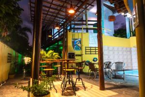 patio ze stołami i krzesłami oraz basenem w obiekcie PV Pousada Passarela da Vila w mieście Itacaré